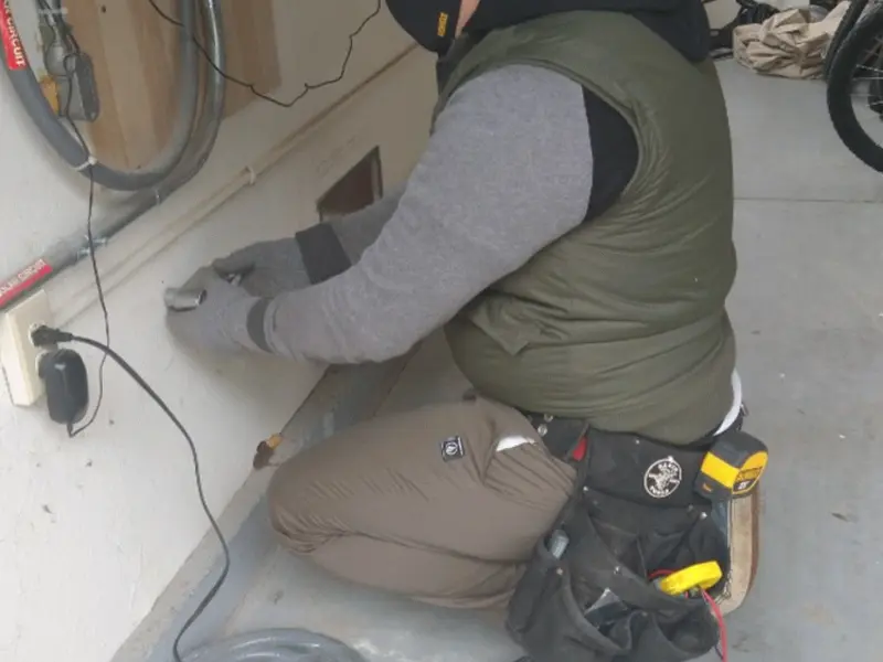 Electrician performing outlet wiring in a Arvada garage
